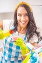 Smiling housekeeper looking into the camera pouring detergent onto a sponge Royalty Free Stock Photo