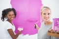 Smiling housemates painting wall pink Royalty Free Stock Photo