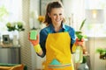 Smiling housewife with cleaning agent and sponge housecleaning