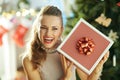 Smiling housewife near Christmas tree shaking Christmas gift Royalty Free Stock Photo