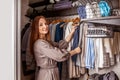 Smiling housewife neatly hanged putting clothes during seasonal cleaning at wardrobe organization