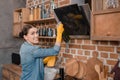 Smiling housewife in rubber gloves cleaning tv set at home