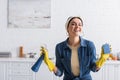 Smiling housewife in rubber gloves holding