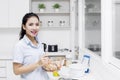 Smiling housewife stirring apple in bowl