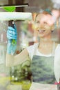 Housewife washing windows with squeegee