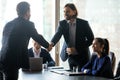 Smiling hr team leader shaking hands with job seeker.