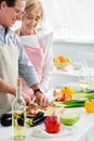 smiling husband cutting vegetables on wooden board