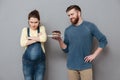 Smiling husband offers his unsatisfied pregnant wife a chocolate cake