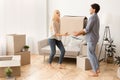 Smiling Husband And Wife Carrying Moving Box Into New Flat