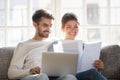 Smiling couple hold paperwork paying bills online