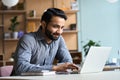 Smiling indian business man working studying on laptop computer at home office. Royalty Free Stock Photo