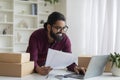 Smiling indian businessman analyzing documents and using laptop in home office Royalty Free Stock Photo