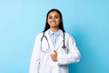 Smiling Indian Doctor Young Woman Gesturing Thumbs Up, Blue Background Royalty Free Stock Photo