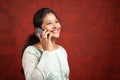 Smiling Indian girl busy talking on mobile phone by looking above showing with copy space - concept of happy customer service and Royalty Free Stock Photo