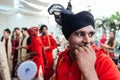 Smiling Indian musician guy wearing red Bandhgala and black Pheta at Indian wedding ceremony in Bangkok, Thailand