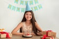 Smiling Indian teenage girl with birthday cake, gift boxes and party hat looking at camera, celebrating holiday Royalty Free Stock Photo