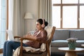 Smiling Indian woman in headphones chatting online, sitting in armchair Royalty Free Stock Photo