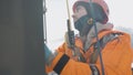 Smiling industrial climber washes windows high altitude outside against background sunlight