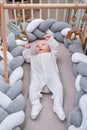 Smiling infant baby boy playing with a wooden mobile suspended above the crib. Happy child playing in bed with toys Royalty Free Stock Photo