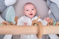 Smiling infant baby boy playing with a wooden mobile suspended above the crib. Happy child playing in bed with toys Royalty Free Stock Photo