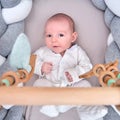 Smiling infant baby boy playing with a wooden mobile suspended above the crib. Happy child playing in bed with toys Royalty Free Stock Photo