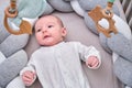 Smiling infant baby boy playing with a wooden mobile suspended above the crib. Happy child playing in bed with toys Royalty Free Stock Photo