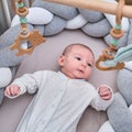 Smiling infant baby boy playing with a wooden mobile suspended above the crib. Happy child playing in bed with toys Royalty Free Stock Photo