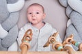 Smiling infant baby boy playing with a wooden mobile suspended above the crib. Happy child playing in bed with toys Royalty Free Stock Photo