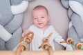 Smiling infant baby boy playing with a wooden mobile suspended above the crib. Happy child playing in bed with toys Royalty Free Stock Photo