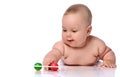 Smiling infant child baby girl kid in diaper is lying on her stomach playing with rattle, touching with hand Royalty Free Stock Photo