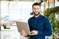 Smiling intelligent man with laptop in hand in office