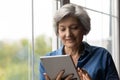 Smiling interested middle aged 60s woman using digital tablet. Royalty Free Stock Photo