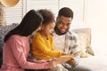 Smiling international parents teach child to read