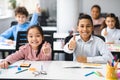 Smiling international schoolchildren showing thumbs up gesture