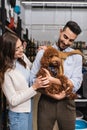 Smiling interracial couple holding poodle in