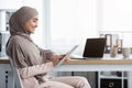 Smiling Islamic Businesswoman Using Digital Tablet While Sitting At Workplace