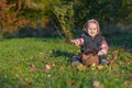 Smiling ittle baby boy is sitting with wicker basket full of walnuts