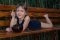 Smiling ittle girl lies on a wooden bench with a berry in her hand. Royalty Free Stock Photo