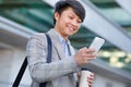 Smiling Japanese office worker man texting on mobile smartphone outside Royalty Free Stock Photo