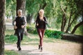 Smiling joggers running together on pavement in sunny park