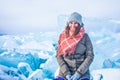 Smiling joyful female wanderer looking in camera while sitting on frozen Baikal lake