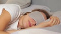 Smiling joyful woman wearing sleeping mask and white T-shirt expressing positiveness while watching pleasant dreams while having