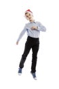 Smiling jumping schoolboy in Santa`s hat. Full height. Christmas mood. Isolated over white background.