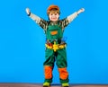 Smiling kid boy in safety helmet and toolbelt raised hands. Little repairman, builder or construction worker with tools Royalty Free Stock Photo