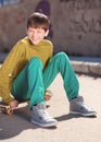 Smiling kid boy sitting on skateboard outdoors Royalty Free Stock Photo