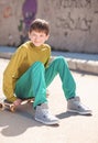 Smiling kid boy sitting on skateboard outdoors Royalty Free Stock Photo