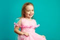 Smiling kid girl in pink dress on blue isolated Royalty Free Stock Photo