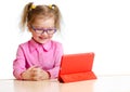 Smiling kid in glasses looking at mini tablet pc screen sitting