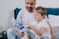 Kid holding fathers day greeting card while sitting near happy father Royalty Free Stock Photo