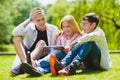 Smiling kids having fun and look to tablet at grass. Children playing outdoors in summer. teenagers communicate outdoor Royalty Free Stock Photo